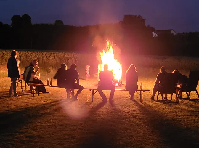 Personen vor Sonnwendfeuer bei Nacht