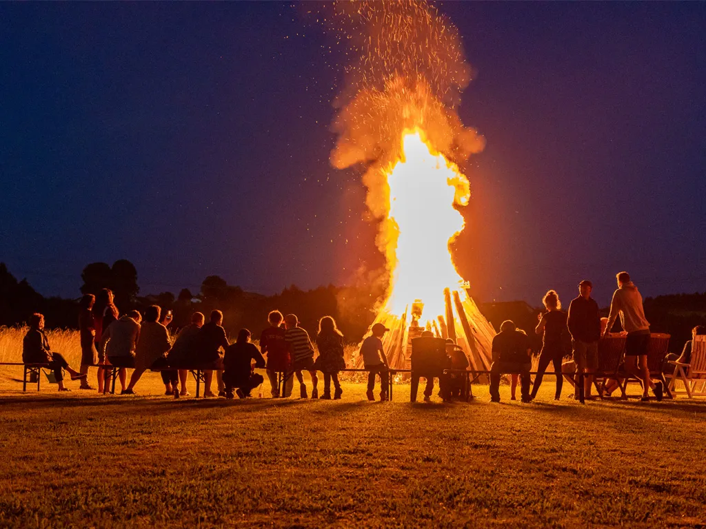 Gäste am hell brennenden Sonnwendfeuer auf dem Vereinsgelände